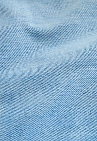 Tissu texturé bleu clair avec des fils tissés visibles horizontalement et verticalement, créant une surface douce et ondulée.