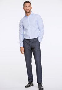Lichtblauw overhemd met lange mouwen en knoopsluiting, gecombineerd met donkergrijze, op maat gemaakte broek en zwarte nette schoenen. Soepele stof, getailleerd design.