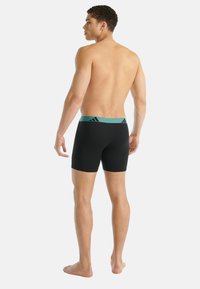 Czarne bokserki z turkusowym pasem w talii ozdobionym logo z trzema paskami z przodu. Gładka faktura i dopasowany krój.