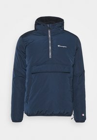 Chaqueta de pullover azul marino con cuello con cremallera, bolsillo delantero y puños elásticos. Fabricada con material suave y resistente a las inclemencias del tiempo. Logo de Champion exhibido.