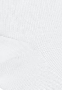 Biała bawełniana skarpetka o ryżowej fakturze, z gładkim szwem palców i wzmocnionym piętą, wyeksponowana pod kątem.