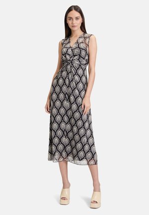 Maxi-jurk in marineblauw met een beige paisleypatroon, met een V-hals, mouwloos ontwerp en geknoopte taille-details. Glad, lichtgewicht stof.