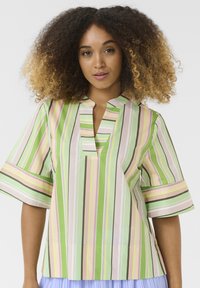 Ribadeeritud pluus roheliste, roosade ja valgete värvidega, millel on vale nööpide rida, lühikesed varrukad ja lõdva lõikega. Sile puuvillane kangast tekstuur.