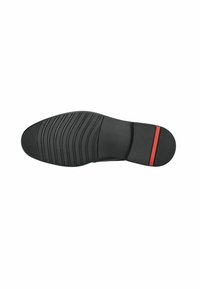 Suela de zapato negra con un patrón texturizado para agarre, forma redondeada y una franja de acento roja en el talón. Material de goma suave.