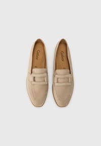 Mocassins en suède beige avec une texture lisse, présentant un détail à double sangle sur le devant et une semelle intérieure rembourrée pour plus de confort.
