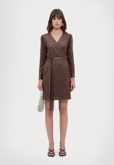 Braunes schimmerndes Wickelkleid mit langen Ärmeln, V-Ausschnitt, tailliertem Gürtel, knielang, kombiniert mit einer kleinen silbernen Tasche und schwarzen Riemchensandalen.