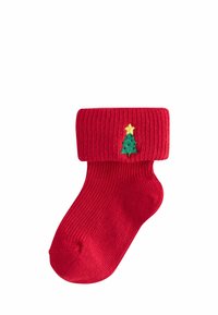 Rote gerippte Socke mit umgeschlagenem Bündchen, das auf der Vorderseite einen kleinen gestickten grünen Weihnachtsbaum und einen gelben Stern zeigt.