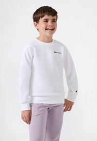 Vit sweatshirt med långa ärmar och rund hals, med en svart "Champion"-logotyp på bröstet och en liten logotyp på ärmslutet.
