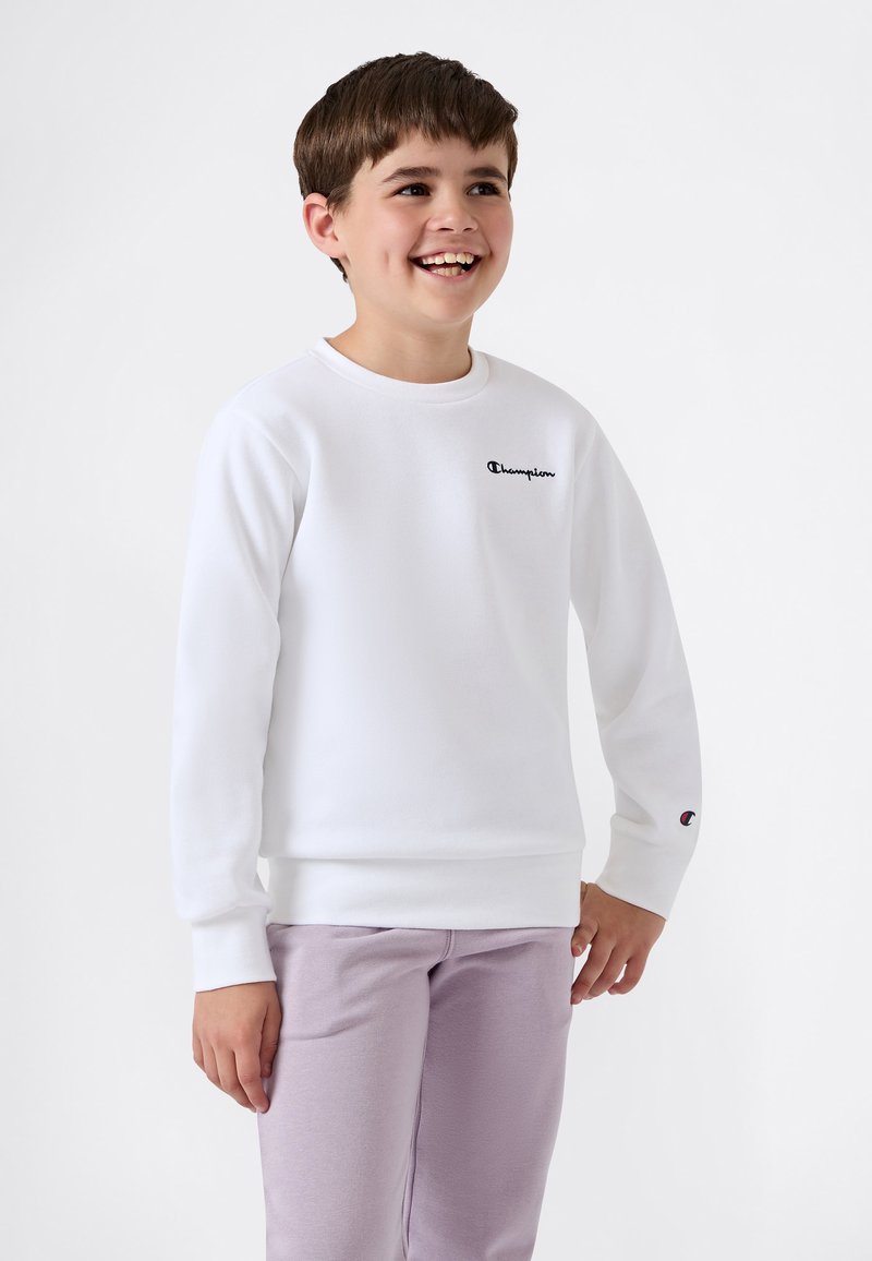 Vit sweatshirt med långa ärmar och rund hals, med en svart "Champion"-logotyp på bröstet och en liten logotyp på ärmslutet.