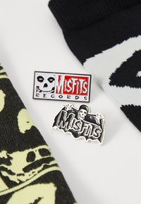 Two Misfits-themed enamel pins: one features a skull with "Misfits Records" in red; the other shows a skull with bat wings in black and white.