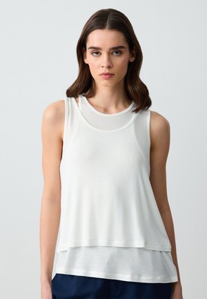 Top bianco a strati con scollo rotondo, caratterizzato da uno strato esterno trasparente e uno strato interno opaco. Tessuto morbido e leggero.