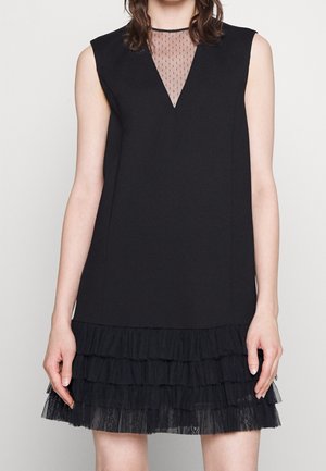 Czarna sukienka bez rękawów z przezroczystym siateczkowym dekoltem w kształcie litery V i warstwowym falbanowym dołem z tiulu. Gładki materiał o strukturalnym kroju.