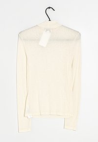 Lange mouwen, lichtbeige top gemaakt van doorzichtig materiaal. Heeft een hoge kraag en een hangtag op de achterkant. Duimt zachte textuur met een iets losse pasvorm.