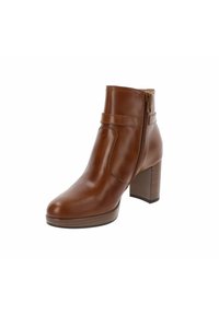 Bottines en cuir marron avec un bout arrondi, une fermeture éclair sur le côté, des coutures décoratives et un talon empilé. Texture lisse avec une finition brillante.