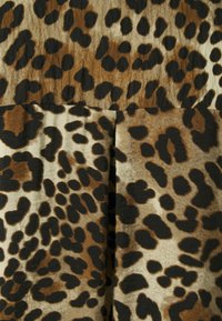 Tessuto con stampa leopardata che presenta un mix di tonalità marroni, nere e beige, con distintive macchie testurizzate che creano un motivo dinamico.