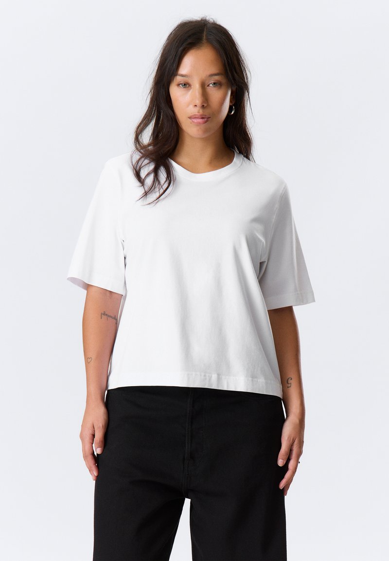 White cotton t-shirt with short sleeves, a rounded neckline, and a relaxed fit. The fabric appears smooth and unembellished.