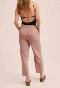 Jasnoróżowe, luźne spodnie z elastycznym pasem, w długości 7/8, z bocznymi kieszeniami i gładką teksturą. W połączeniu z czarnym obuwiem.
