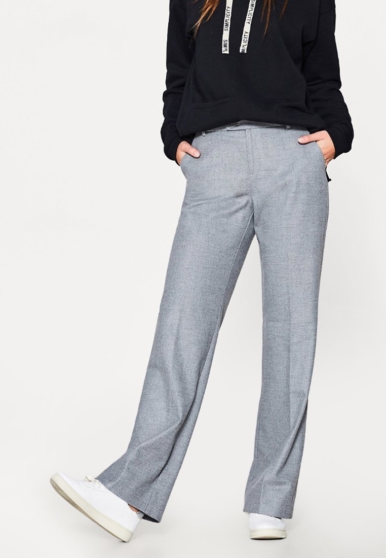 Pantalons gris ajustés avec une texture lisse, coupe décontractée et poches latérales, associés à un hoodie noir et des baskets blanches.