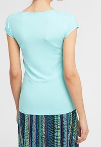 Camiseta de manga corta de color azul claro con cuello redondo, hecha de una tela suave, combinada con una falda de rayas multicolores con un patrón.