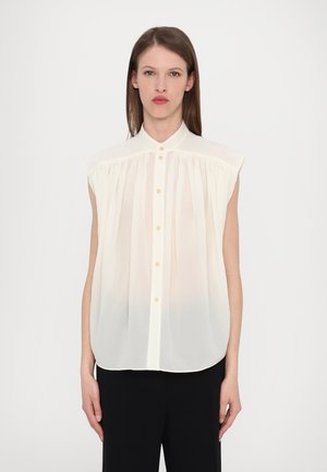 IVORY ilma varrukate ja kraega blouse, nuppude esiosa ja voltidega tekstuur. Pehme, kerge materjal. Üksik, kergelt ümardatud äär.