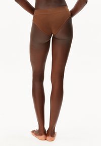 Bruine, hoog uitgesneden slip van gestructureerde stof, met een gladde tailleband en een eenvoudig ontwerp aan de achterkant, getoond op blote benen.