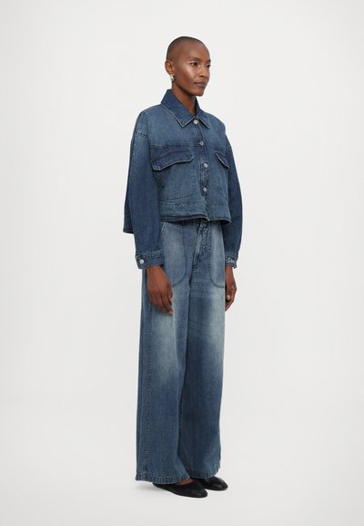 Jeans jakna z gumbom in dvema sprednjima žepoma, v kombinaciji s širokima denim hlačami. Obe v gradientni modri prani. Gladka tekstura.