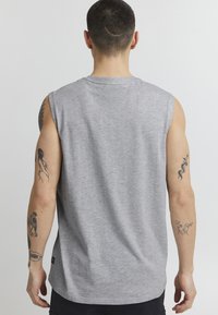 Graues ärmelloses T-Shirt aus Baumwolle, mit rundem Ausschnitt, glatter Textur und sichtbaren Nähten auf der Rückseite.