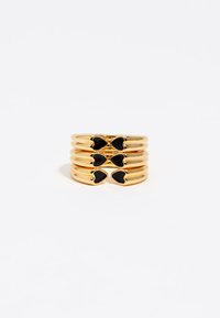 Anillos apilados de color dorado con acentos negros en forma de corazón, con una textura suave y pulida y un diseño simple y moderno.
