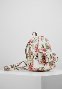 Bloemenrugzak met een wit leerachtig materiaal, roze en groene bloemmotieven, afgeronde vorm en een accent van goudkleurig beslag.