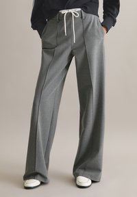Szare spodnie o szerokich nogawkach wykonane z fakturowanej tkaniny, z plisami i elastycznym pasem; posiadają sznurek do wiązania oraz boczne kieszenie.