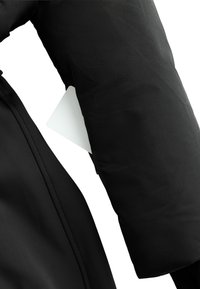 Czarna kurtka puchowa o gładkiej, matowej fakturze, z widoczną białą metką wszytą w szew rękawa. Zamek jest ukryty.