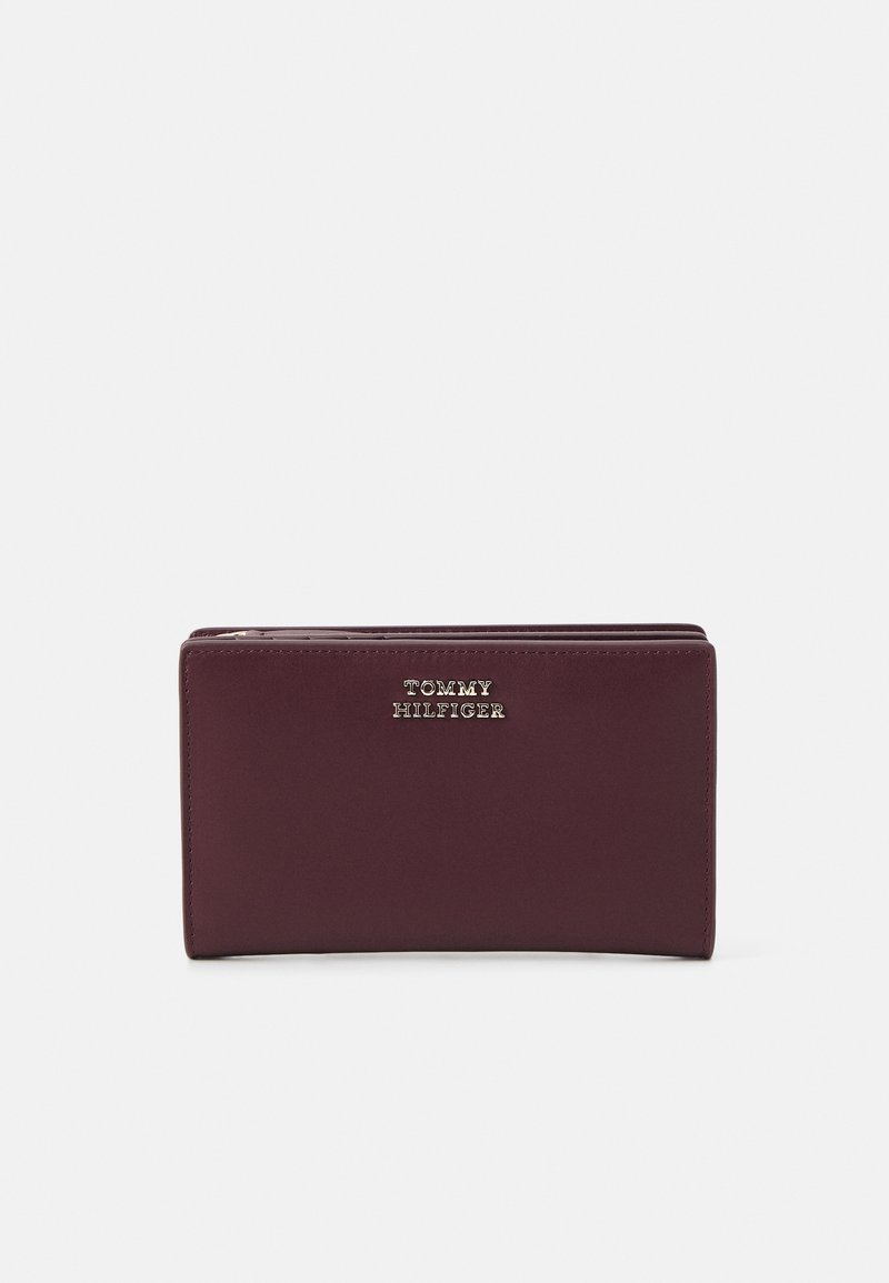 Burgundy leather wallet with gold embossed “TOMMY HILFIGER” logo, rectangular shape, smooth texture, and stitching along the edges.
