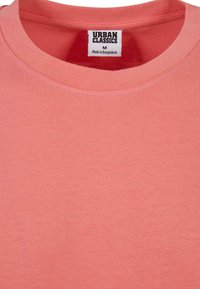 Korall rózsaszín pamut póló kerek nyakkal, varrott aljjal és "Urban Classics" címkével, M-es méret, Bangladesben készült.