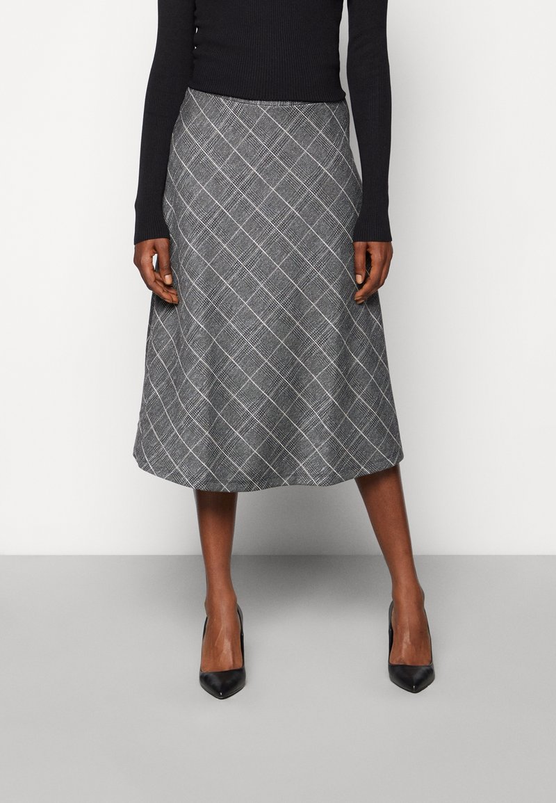 A-siluetová sukně s černobílým kostkovaným vzorem, vyrobená z texturované látky, s délkou po kolena a jemným leskem, doplněná černými lodičkami.