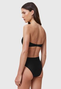 Divertente costume da bagno nero a due pezzi con top senza spalline e slip a vita alta. Texture liscia con un design elegante e hardware minimale.