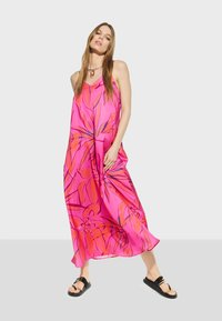 Pink floral maxi dress with a loose fit, featuring vibrant orange patterns, adjustable straps, and paired with black strappy sandals.