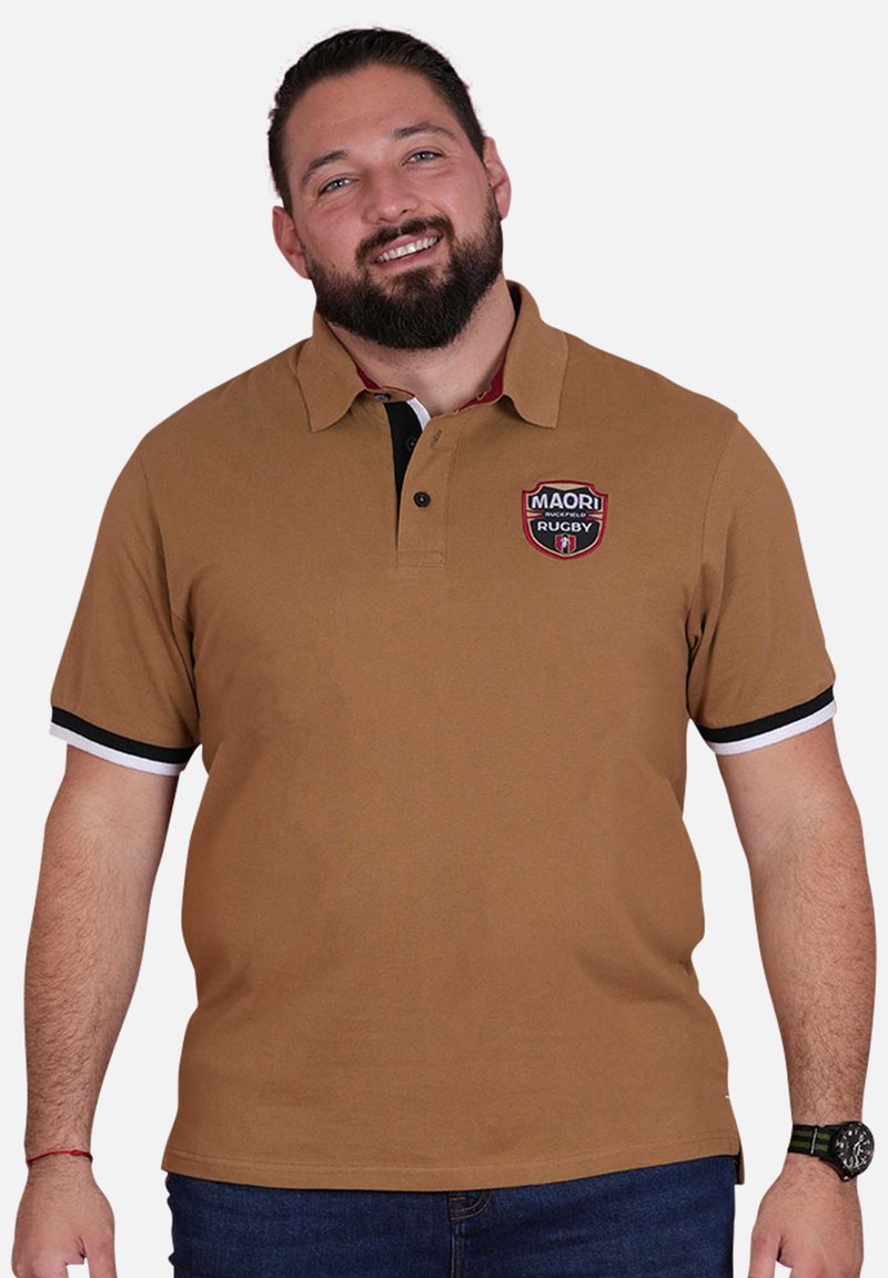 Polo marron avec un col, accents rayés noir et blanc sur les manches, avec un logo brodé rouge et noir sur la poitrine.