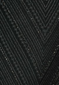 Tissu noir avec un motif en chevrons, présentant des rayures texturées et des accents métalliques éparpillés, créant un design géométrique.
