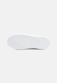 White sneaker sole with a textured, wavy pattern. Rounded edges and a rectangular accent near the heel. Clean design and minimalistic style.
