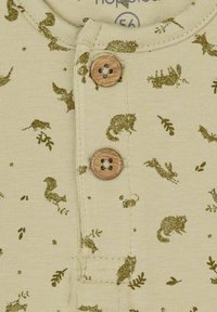 Lichtbeige stoffen romper met een groene dieren- en plantenprint. Het heeft twee houten knopen en een ronde halsontwerp.