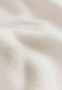 Bela flisasta tkanina z mehkimi, texturiranimi površinami, ki ima sijoč, enakomeren vzorec majhnih vlaknin in blage gube.