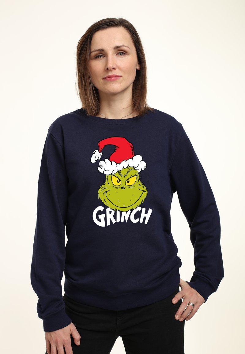 Sudadera azul marino con un gráfico del Grinch caricaturesco, que lleva un gorro de Papá Noel rojo con un borde de piel blanca, y con un gran texto blanco que dice "GRINCH" debajo.