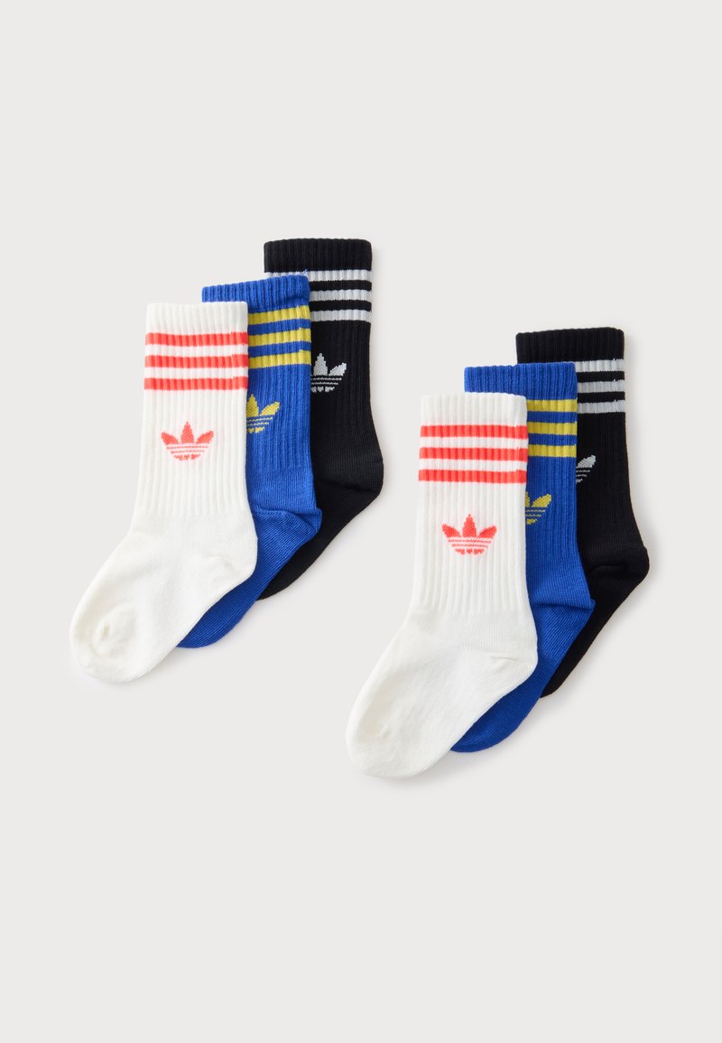 Dva sety po troch Adidas crew ponožkách v bielej farbe s červenými pruhmi a logom, modrej s žltými pruhmi a logom a čiernej s bielymi pruhmi a logom.