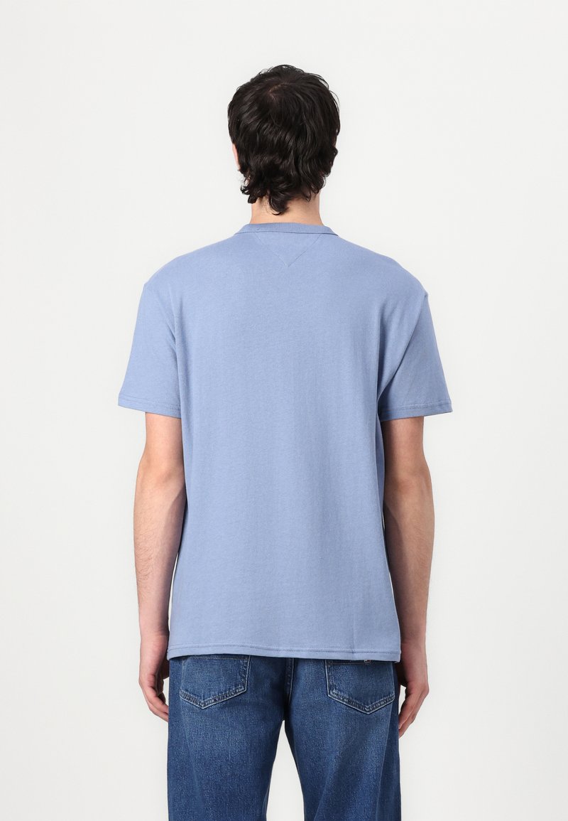 T-shirt bleu clair à manches courtes avec un col rond, fabriqué en coton doux. Détails de couture visibles au dos, porté avec un jean bleu.