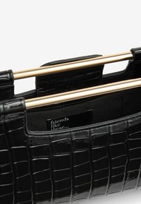 Bolso de cuero sintético de cocodrilo negro con un diseño estructurado, acentos metálicos dorados y una superficie texturizada con una etiqueta de interior de tela.