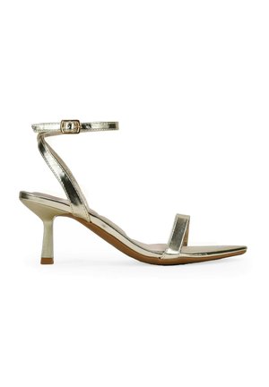 Sandal de tacón alto metálico dorado con una delgada correa en el tobillo, punta abierta y diseño de punta afilada. Presenta un tacón delgado de 3 pulgadas y un estilo minimalista.