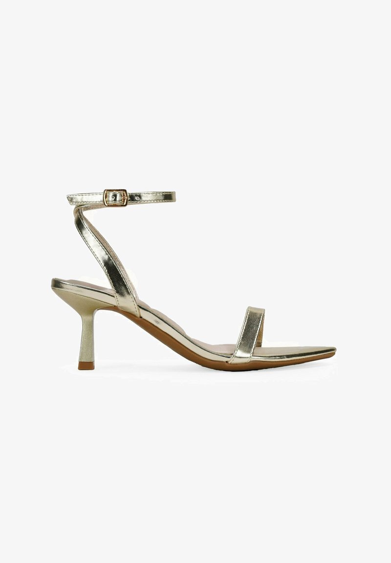 Sandal con tacco alto in metallo dorato, dotata di una sottile cinghia alla caviglia, punta aperta e design a punta. Presenta un tacco sottile di 3 pollici e uno stile minimalista.