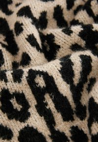 Material tricotat bej cu un model de imprimeu leopard negru, având o textură moale. Finish pufos cu forme variate în design.