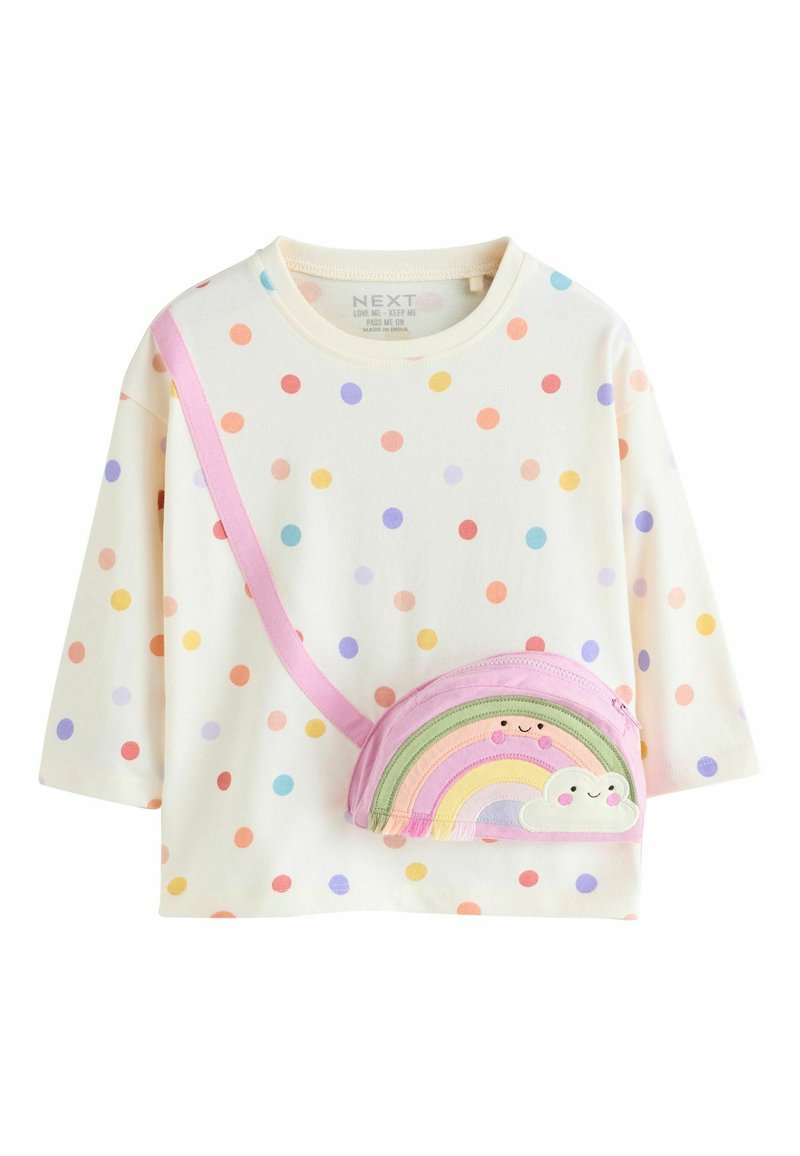 Cremefarbenes Langarmshirt mit mehrfarbigen Punkten, kombiniert mit einer kleinen rosa Tasche in Regenbogenform mit bestickten Wolkendesigns.