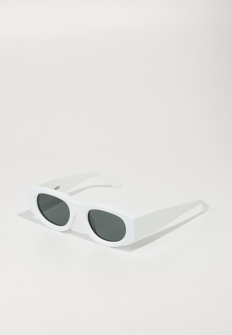 Baltas taisnstūra formas saulesbrilles ar tumši pelēkiem lēcām un biezām rāmām, kas izceļas ar matētu apdari un elegantiem, leņķiskiem tempļiem.